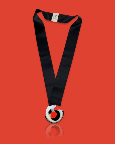 Minimal blob-shaped long necklace with a small white red pendant and black silk ribbon fastening.