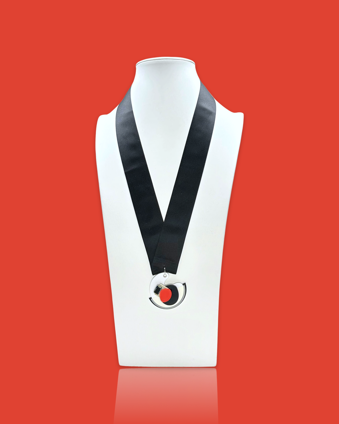 Minimal blob-shaped long necklace with small white red pendant on display, featuring acrylic hardware and silk ribbon fastening.