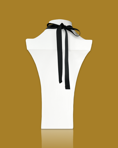 Abstract elegant necklace in creamy color with black and gold pendant on display.