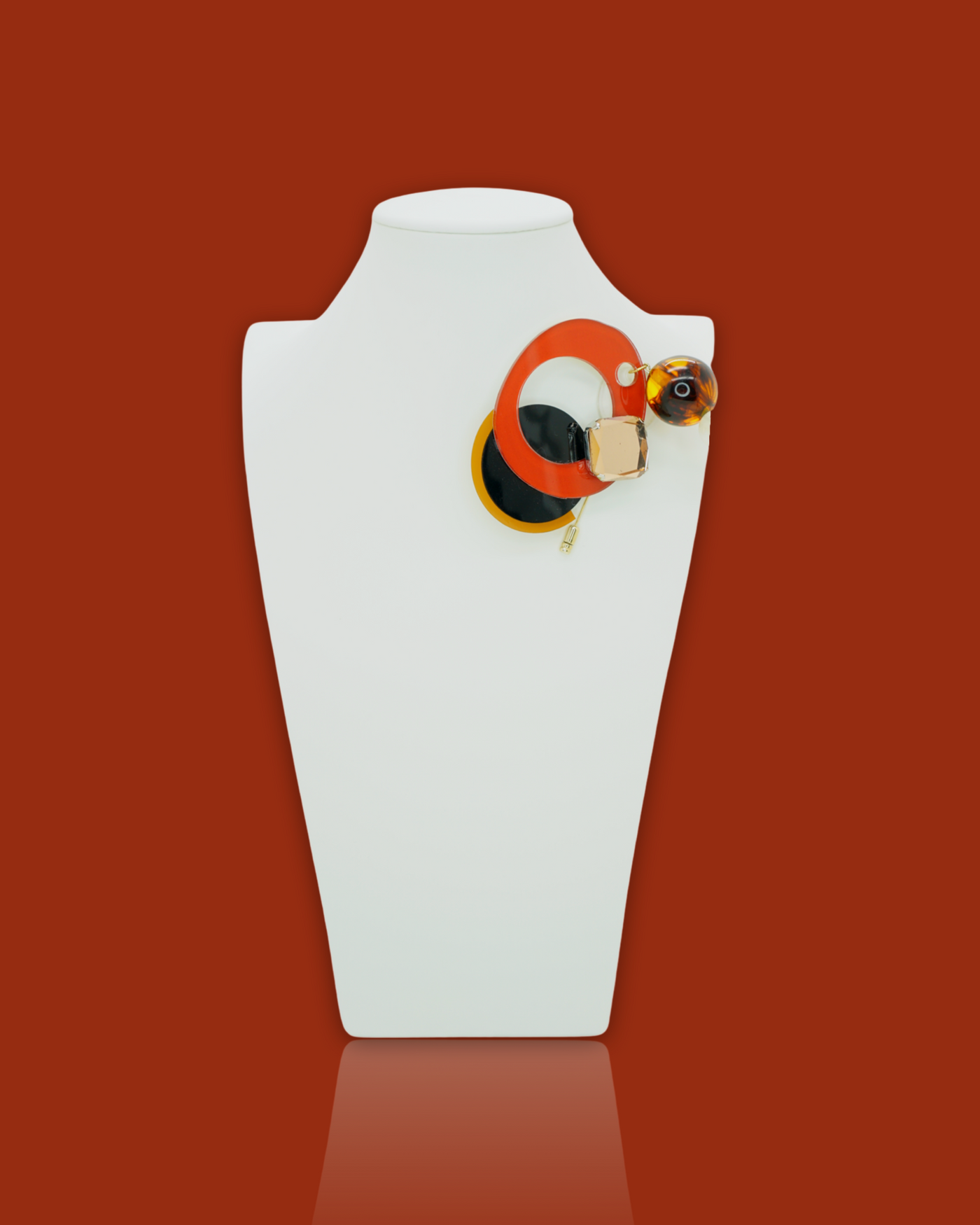 Elegant fashion irregular-shaped cherry-coloured brooch with beads and sequins, on white display.