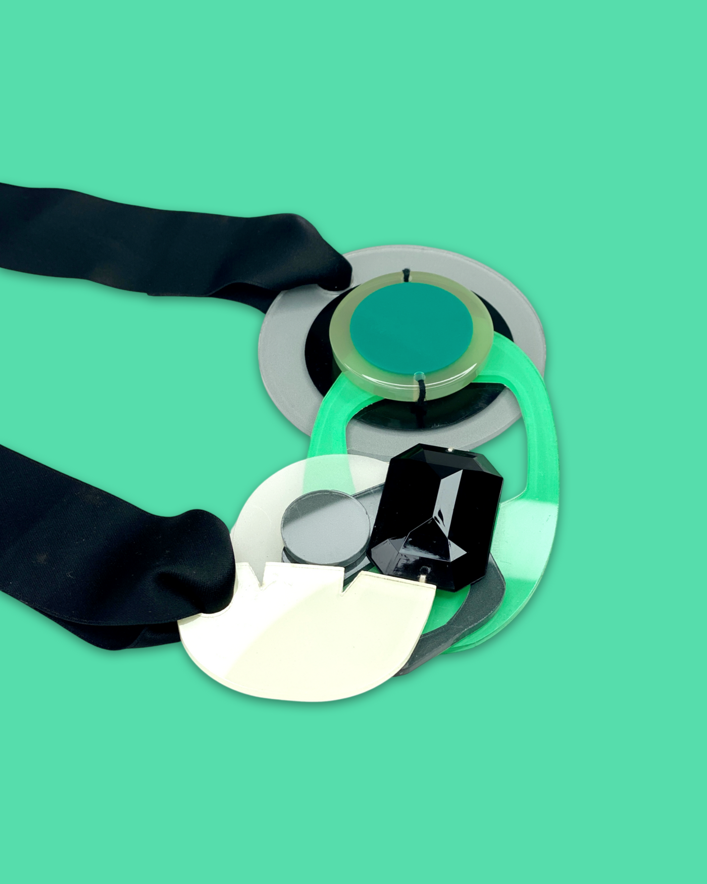 Artistic bold fashion necklace with oversized seafoam pendant and black rhinestone accents, featuring irregular acrylic shapes and silk ribbon fastening.