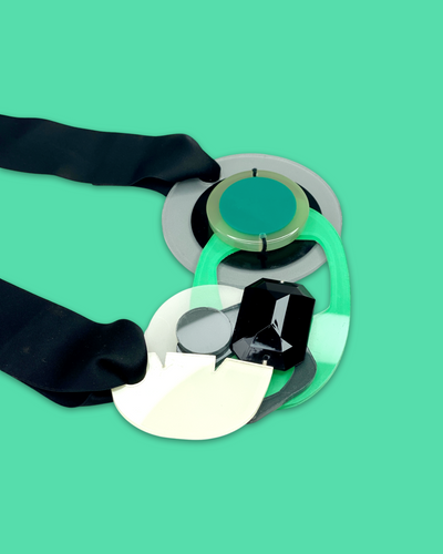 Artistic bold fashion necklace with oversized seafoam pendant and black rhinestone accents, featuring irregular acrylic shapes and silk ribbon fastening.
