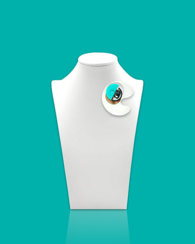 Geometric-shaped trendy brooch in cyan and white with abstract design on display stand.