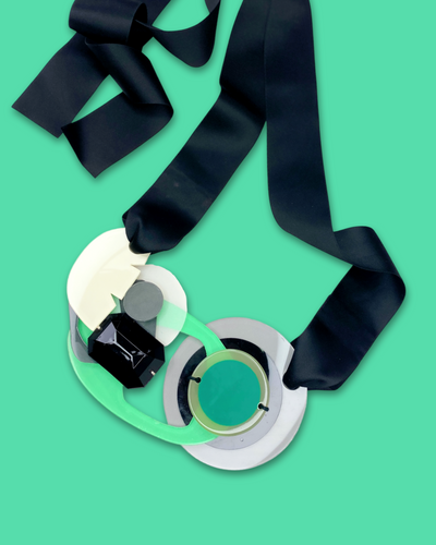 Artistic bold fashion necklace in seafoam color with oversized geometric pendant and black silk ribbon fastening.