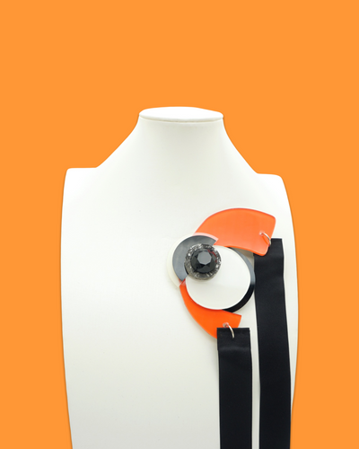 Funky abstract shape necklace brooch in tiger color with acrylic and polymer clay accents on a mannequin.