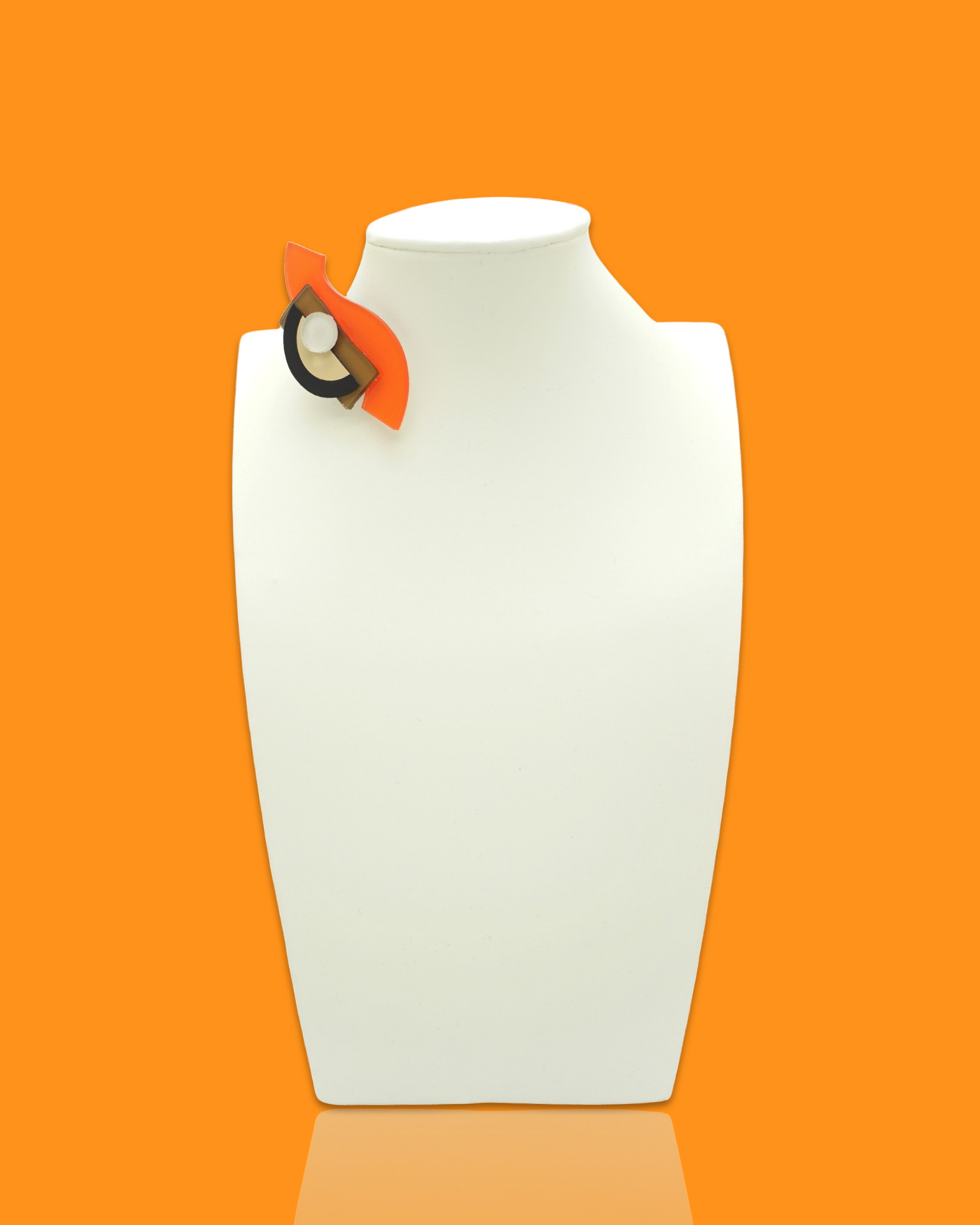 Small geometric-shaped tiger-colored brooch on a white display mannequin.