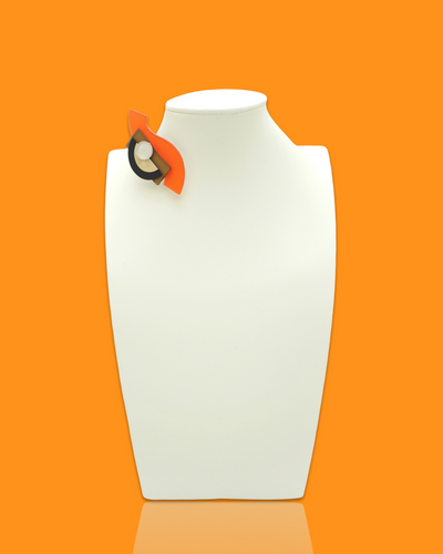 Small geometric-shaped tiger-colored brooch on a white display mannequin.