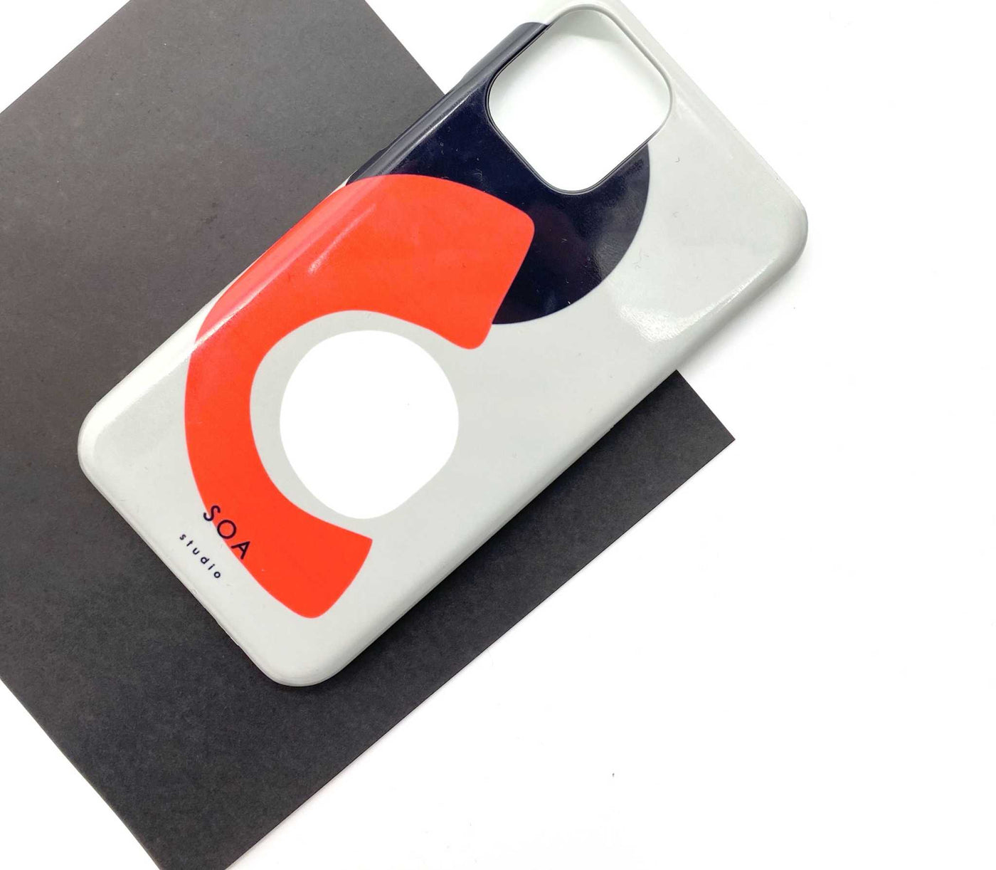 Orange phone case with abstract design on a black surface.